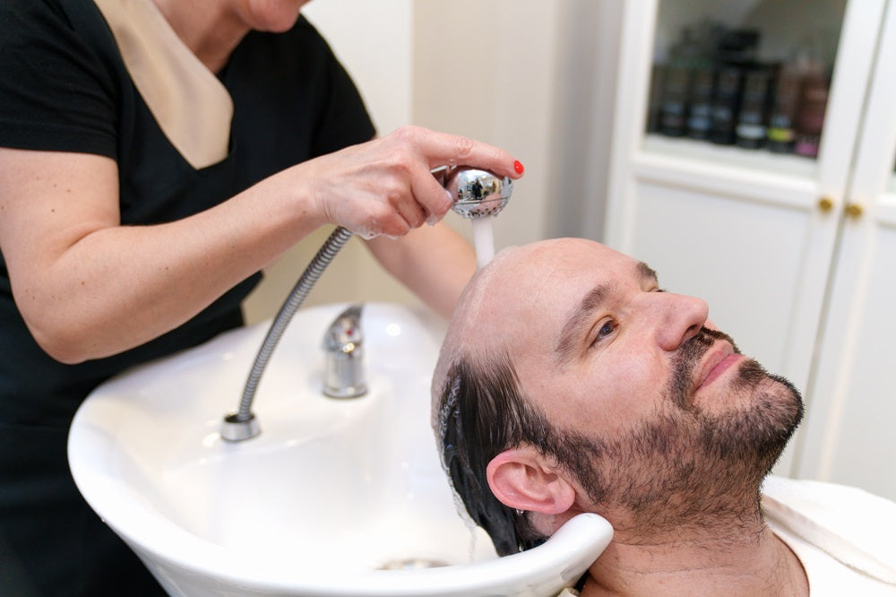 bald man washing head with warm water