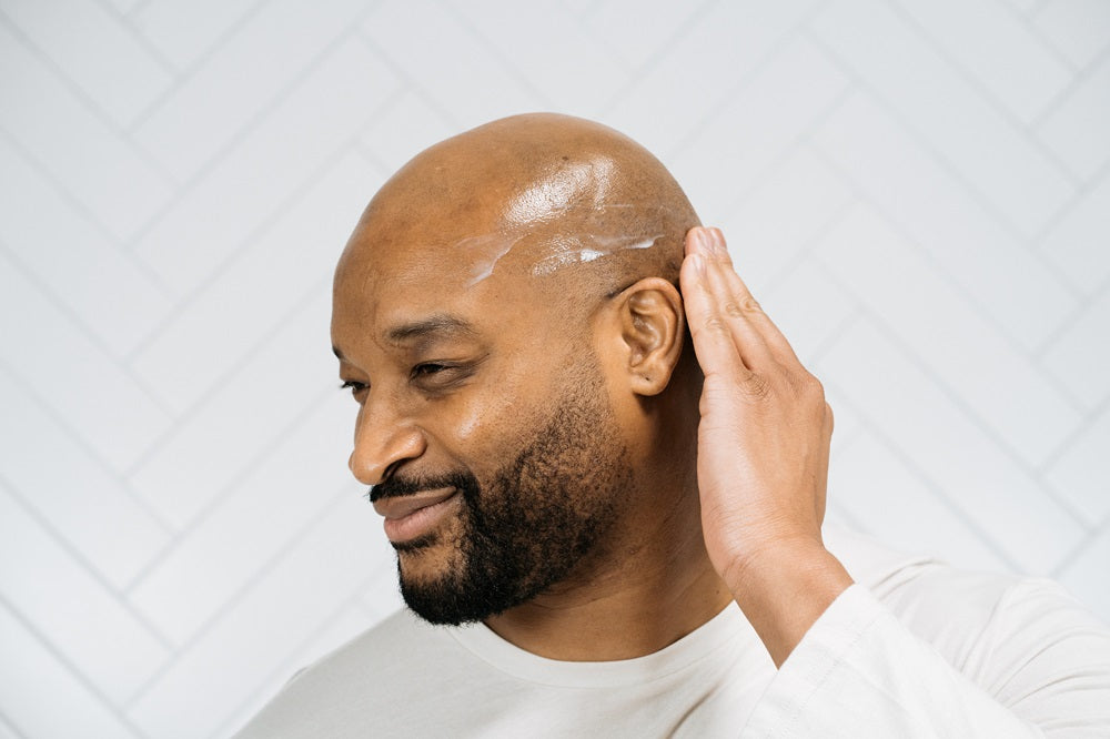 bald man applying moisturizer on scalp