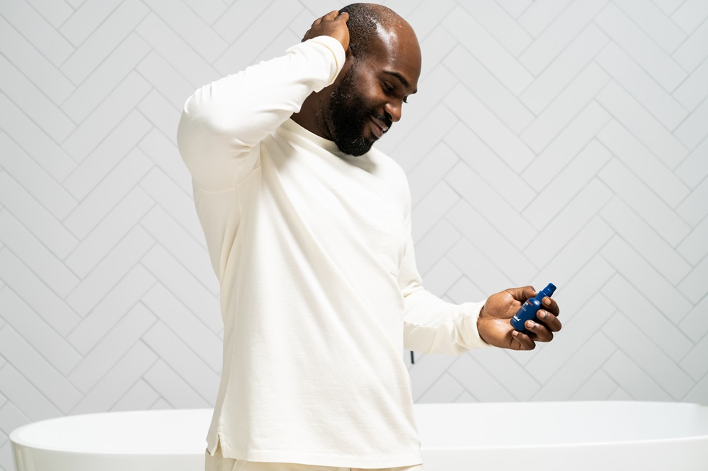 bald man applying moisturizer after head shaving