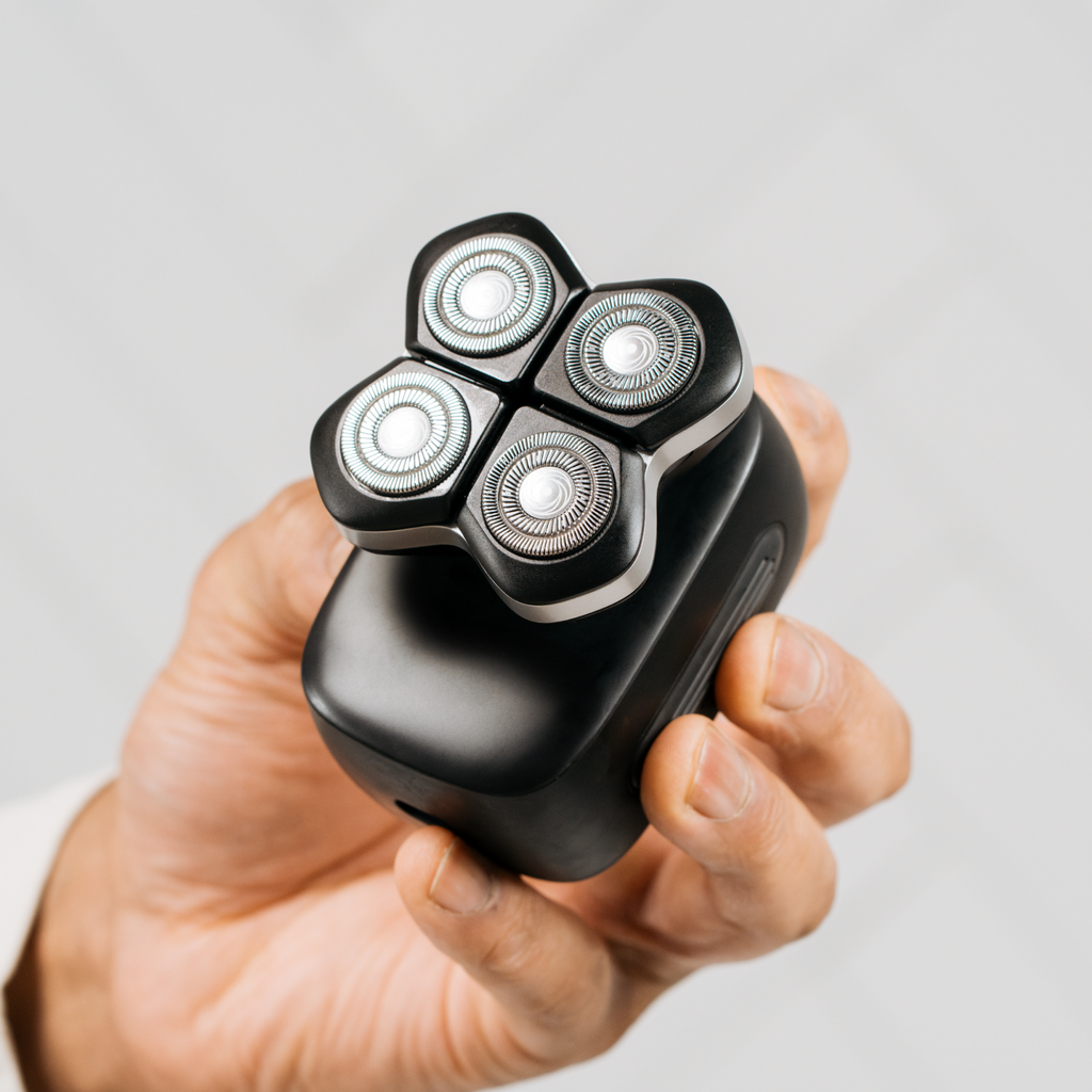 Hand holding a Freebird FlexSeries® Pro Shaving Kit with black head shaver and Four-Blade System against a light gray background.